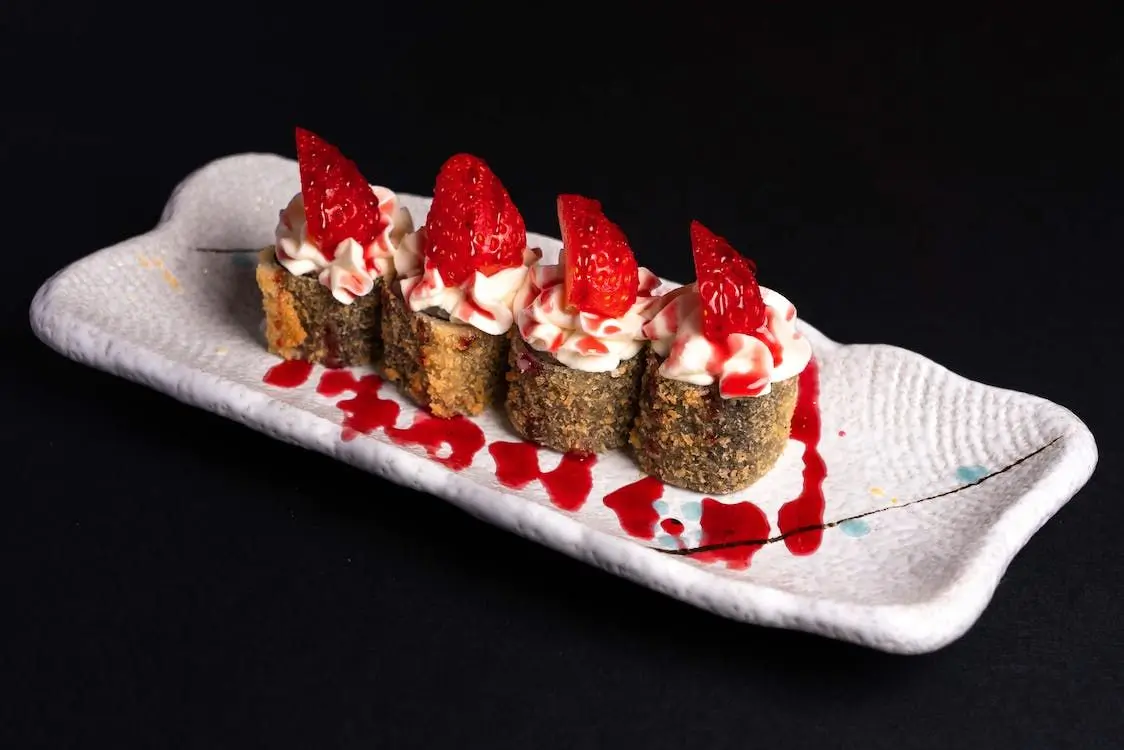 Strawberry Cream Sushi Roll features sushi rolls with a crispy exterior, topped with cream and fresh strawberries, drizzled with red sauce at Sushi Town, a Japanese restaurant in San Jose