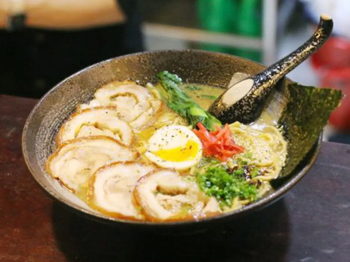 Tonkotsu Ramen features ramen in savory pork bone broth, loaded with slices of chashu pork, a soft - boiled egg, fresh vegetables, shredded red ginger, and chopped scallions at Sushi Town, a Japanese restaurant in San Jose